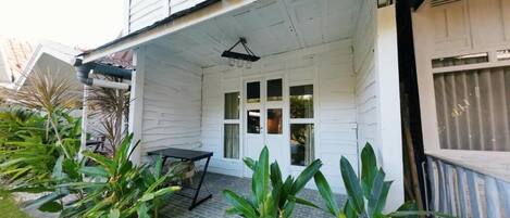 A white house with a covered porch, a small table, and potted plants.