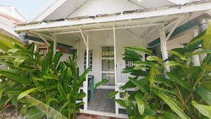 A white building with a covered porch and a brick entrance. - Habana Hotel  (Kuta)