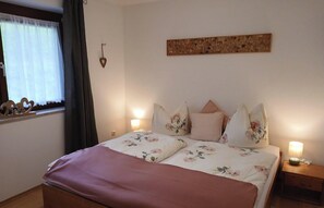 Ein Schlafzimmer mit einem Bett, floraler Bettwäsche, einem Nachttisch mit Lampe und einem Wanddekor.