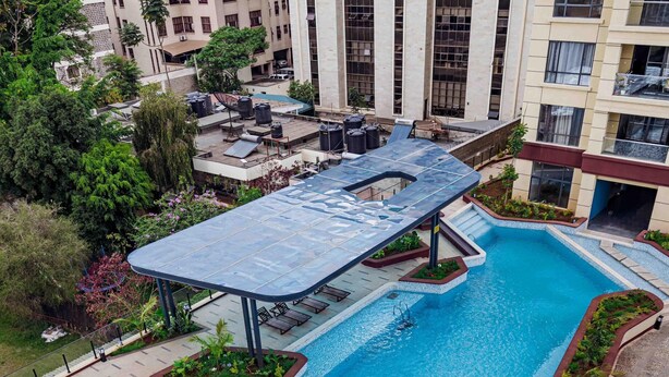 Une piscine sur le toit, dotée d’une terrasse ensoleillée et entourée de verdure.