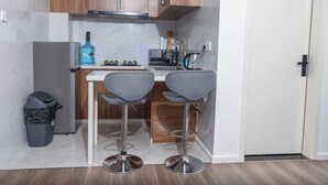 Une cuisine compacte avec des meubles en bois, une hotte en acier inoxydable, une cuisinière à gaz, un évier et deux tabourets de bar.