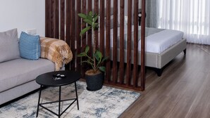 Une chambre moderne avec un canapé, une petite table, une plante en pot, un lit et une cloison en bois.