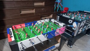Une table de baby-foot ornée des logos des équipes et une table aux couleurs du Real Madrid.