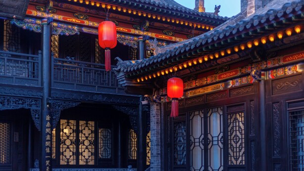 Un edificio tradicional chino con detalles arquitectónicos ornamentales, incluyendo elaborados trabajos en madera y faroles decorativos.