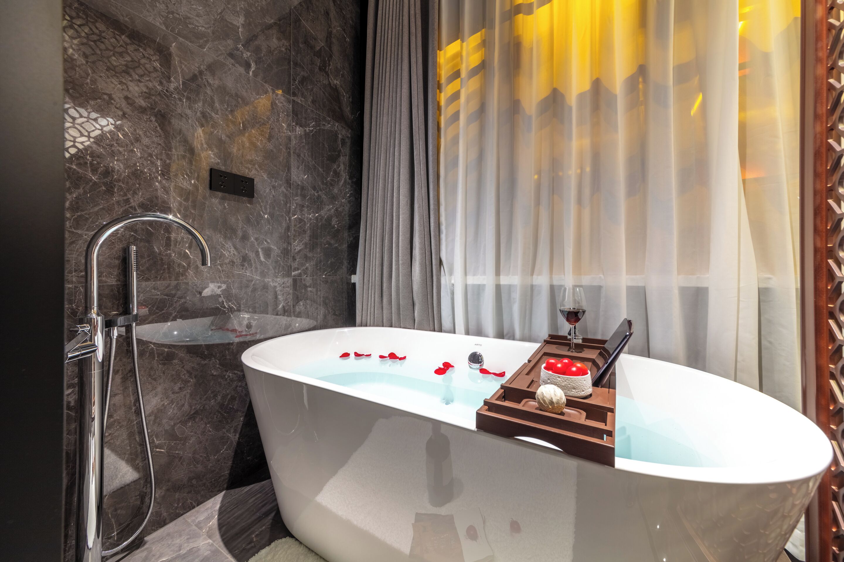 A modern bathroom with a freestanding bathtub, a shower, and a marble wall.