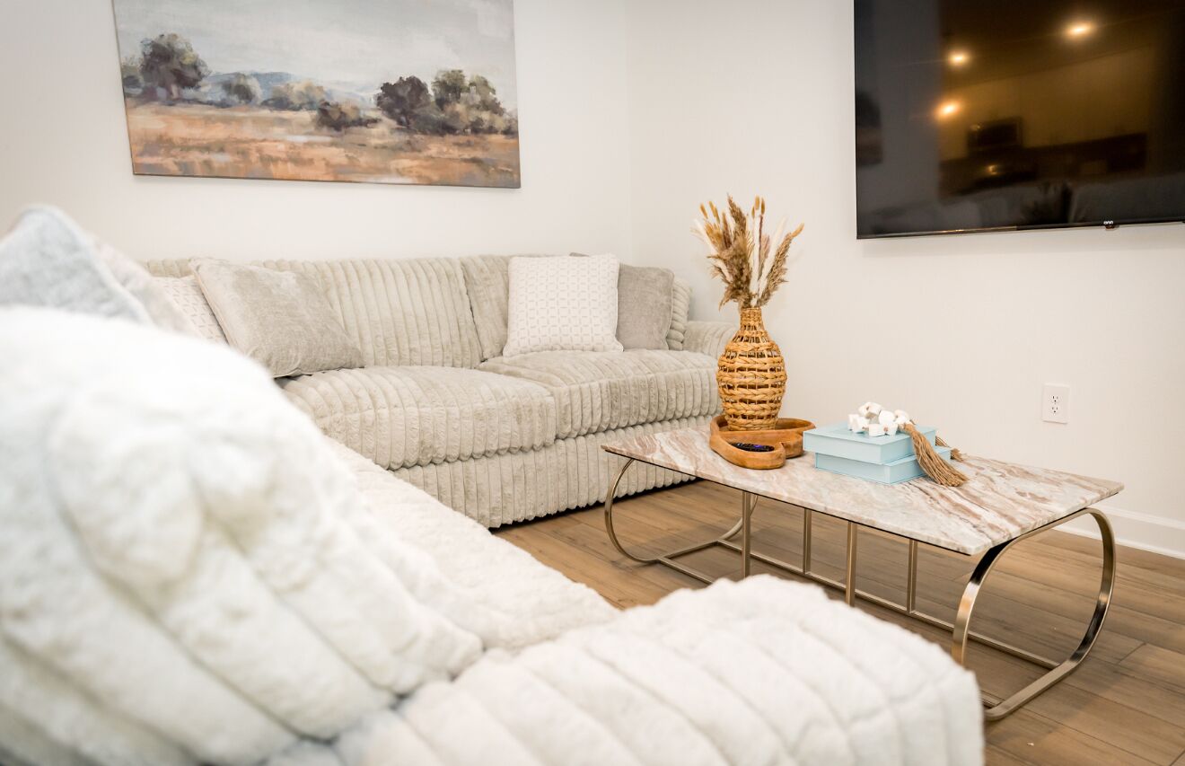 Un salon avec un canapé, une table basse et un tableau accroché au mur.