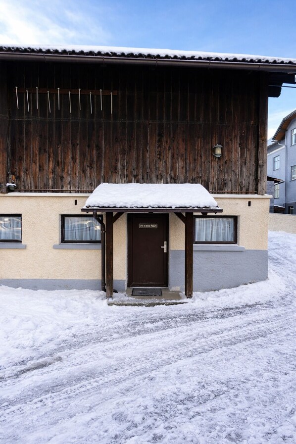 Un bâtiment à l’extérieur en bois et dont l’entrée est recouverte de neige.