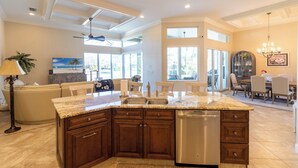 A spacious kitchen with a granite countertop, wooden cabinets, and a built-in dishwasher. - Waterfront, Private Pool, Close to Beaches, Best of Marco! (Marco Island)