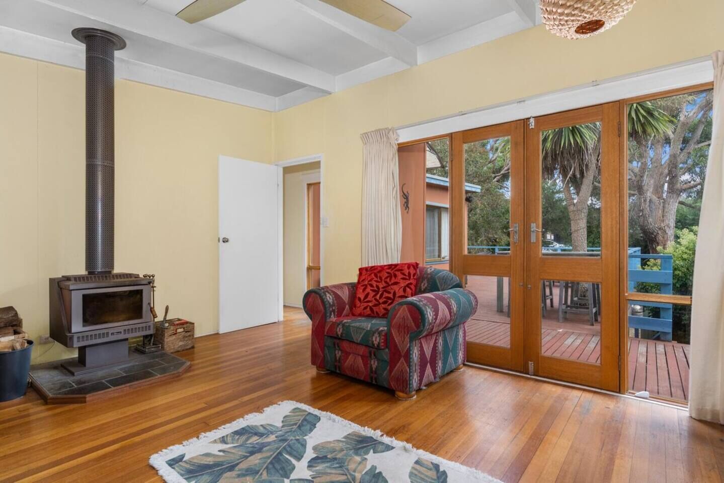 A living room with a wood-burning stove, a patterned sofa, and a view of the outdoors through a sliding glass door.