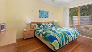 A bedroom with a bed, nightstands, a ceiling fan, and a window with curtains. - The Lohr Shack - 150 metres from the Beach (Inverloch)