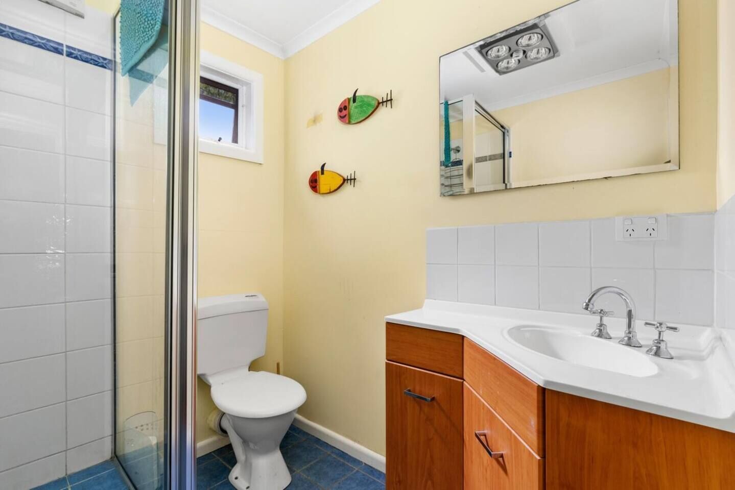A bathroom with a toilet, sink, and mirror.