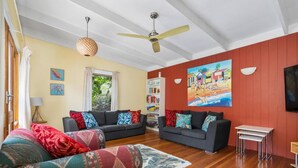 A living room with two sofas, a ceiling fan, a bookshelf, and a painting on the wall. - The Lohr Shack - 150 metres from the Beach (Inverloch)