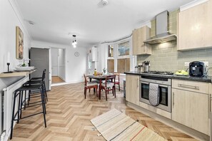 Eine moderne Küche mit Holzboden, einem Essbereich mit Stühlen und einem eingebauten Backofen.