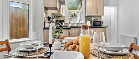 En frukostuppdukning med ett bord för två personer, inklusive tallrikar, glas och croissanter.
