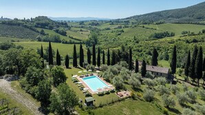 A pool surrounded by lounge chairs and umbrellas, with a view of rolling hills and vineyards. - Podere le Lune with Pool, San Gimignano (San Gimignano)
