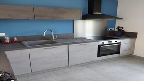 A modern kitchen with grey cabinets, a stainless steel sink, and a built-in oven.