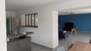 A modern living room with a TV, seating area, and a dining space.