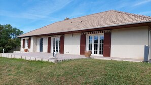 A two-story house with a tiled roof, large windows with shutters, and a front porch.