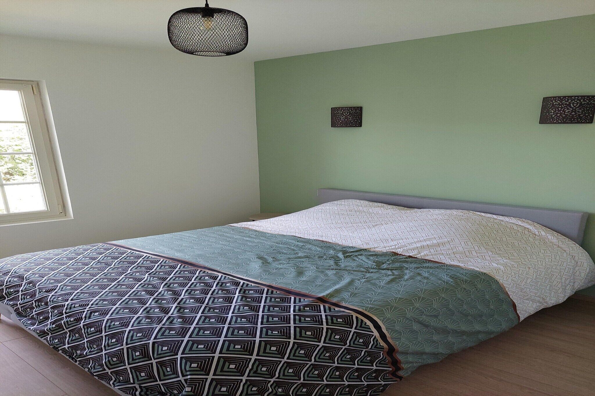 Une chambre à coucher avec un lit, une fenêtre et un luminaire suspendu.