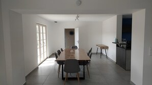 A spacious dining area with a long table, chairs, and a view of the kitchen.