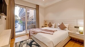 Ett hotellrum med en stor säng, ett nattduksbord, en tv och en skjutdörr i glas som leder ut till utsidan.
