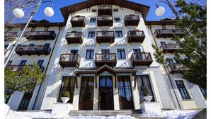 Un hotel de varios pisos con balcones, ventanas amplias y un suelo cubierto de nieve.