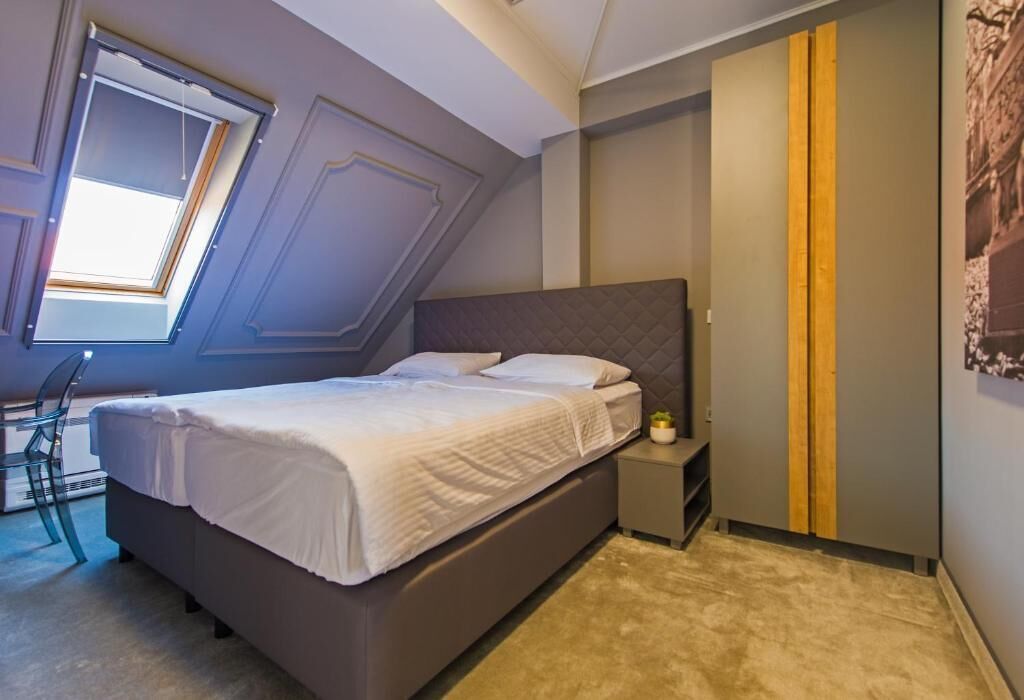 Una camera da letto con un letto, un comodino, una sedia e una finestra.
