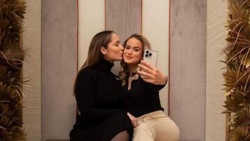 Two people sitting on a bench with a modern design, taking a selfie.