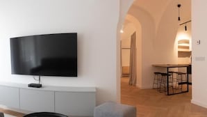 Un salon moderne avec un téléviseur à écran plat fixé au mur, un canapé gris et un plancher en bois.