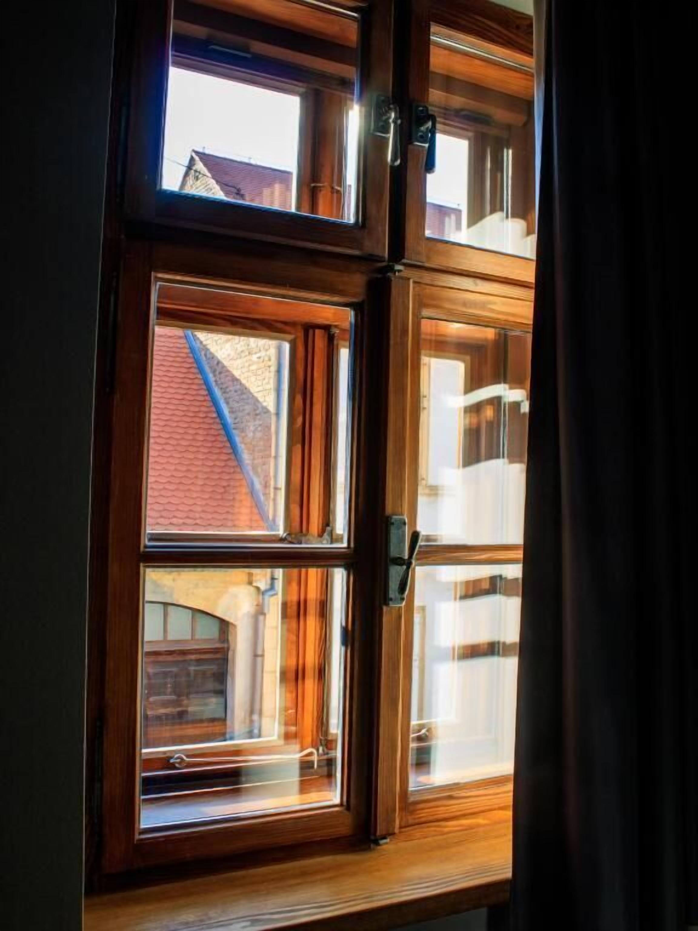 Ein Fenster mit Holzrahmen und Blick auf ein Backsteinhaus.