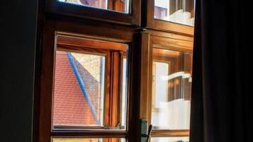 Ein Fenster mit Holzrahmen und Blick auf ein Backsteinhaus.