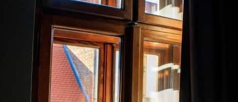 A window with a wooden frame and a view of a brick building outside.