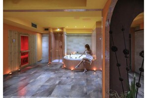 Un espace bien-être comprenant une grande baignoire, un sauna en bois et un sol carrelé.