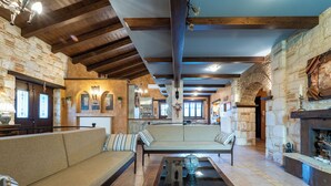 A spacious living area with a stone fireplace, wooden beams, and a sofa with striped cushions. - If you want to combine calmness and art , Arthouse is for you (ζακυνθος)