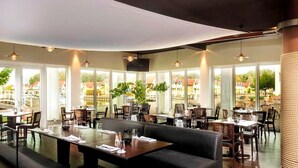 Un restaurant avec de grandes fenêtres, des tables et des chaises.