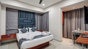 A modern hotel room with a large bed, a wooden headboard, a ceiling fan, a desk with a chair, and a television. - Hotel Samarth Elite Baner (Pune)