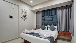 A modern hotel room with a large bed, a headboard with a geometric pattern, and a wall-mounted air conditioning unit. - Hotel Samarth Elite Baner (Pune)