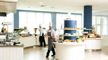A modern kitchen with white cabinetry, a central island with food items, and a large blue pillar.