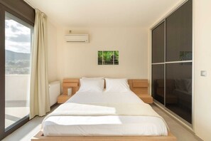 Ein modernes Schlafzimmer mit einem großen Bett und Blick auf die Stadt, inklusive einer Schiebetür.