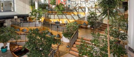 A spacious indoor atrium with multiple seating areas, a staircase, and potted plants.
