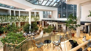 A spacious indoor atrium with a high ceiling, glass roof, and multiple levels.