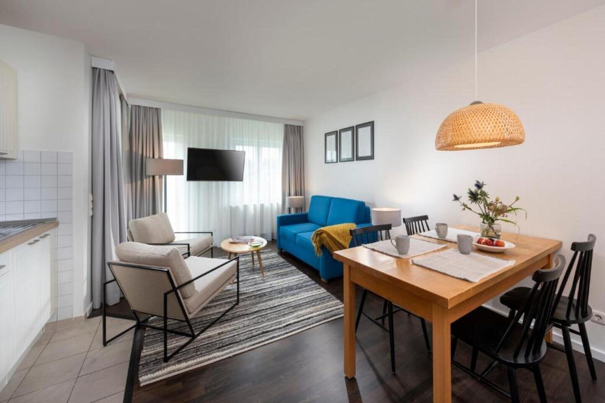 Ein modernes Wohnzimmer mit einem blauen Sofa, einem Holzessttisch und einem an der Wand befestigten Fernseher.