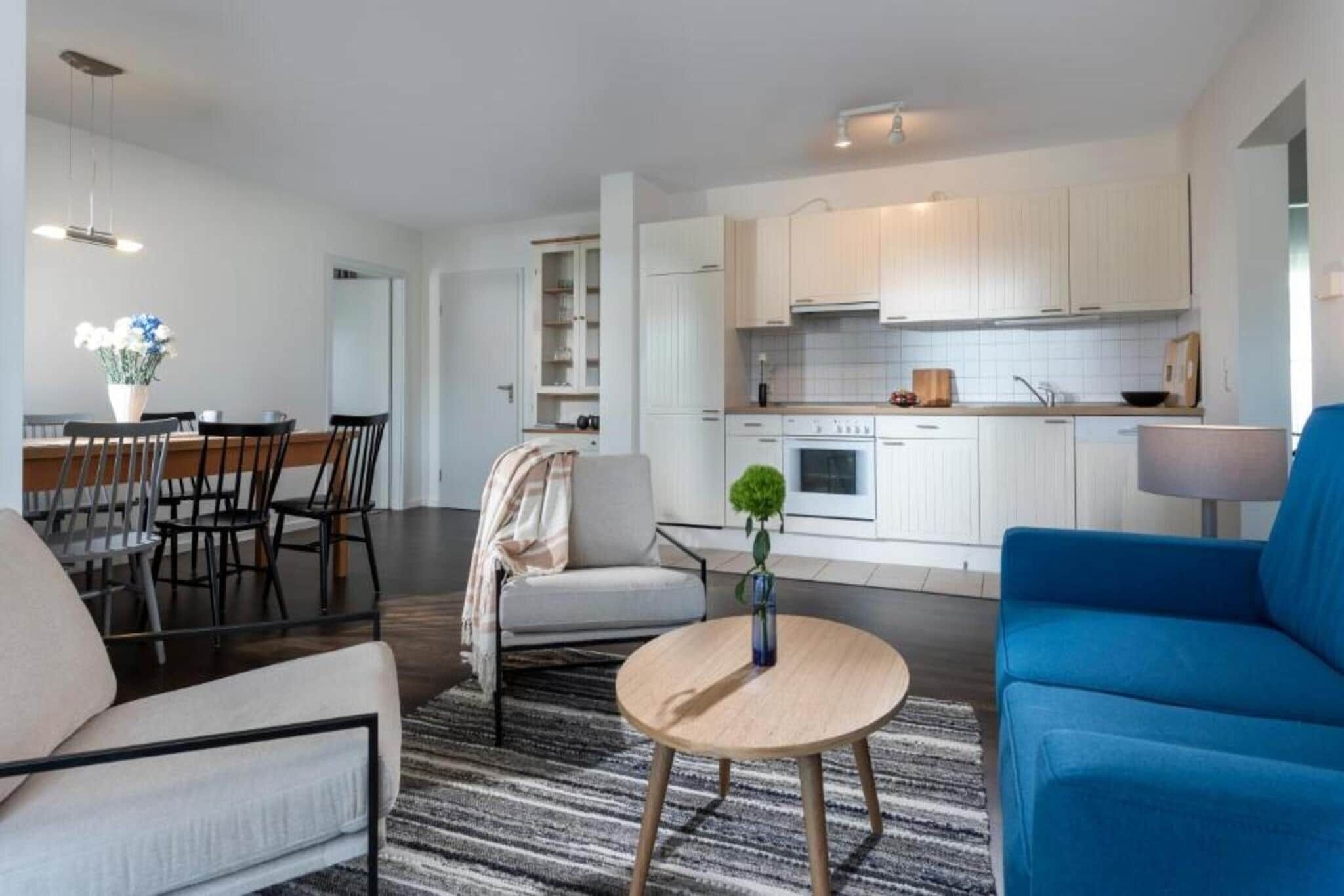 Un salon moderne comprenant un canapé, une table basse ronde et un coin repas avec des chaises et une table.