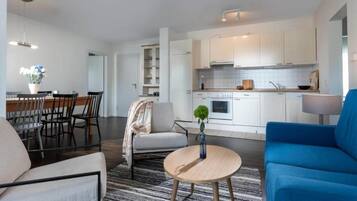 Un salon moderne comprenant un canapé, une table basse ronde et un coin repas avec des chaises et une table.