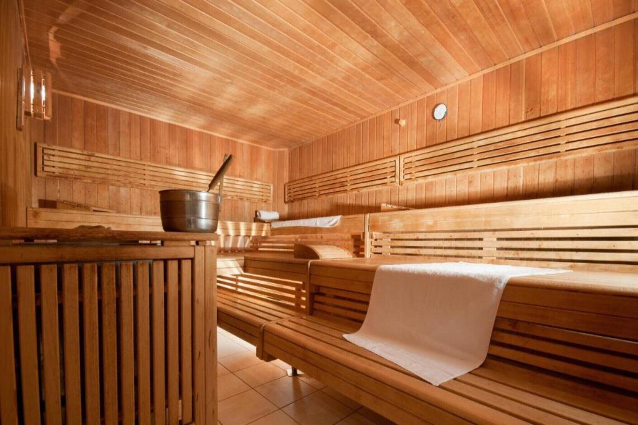 A sauna with wooden benches and a central heating unit.
