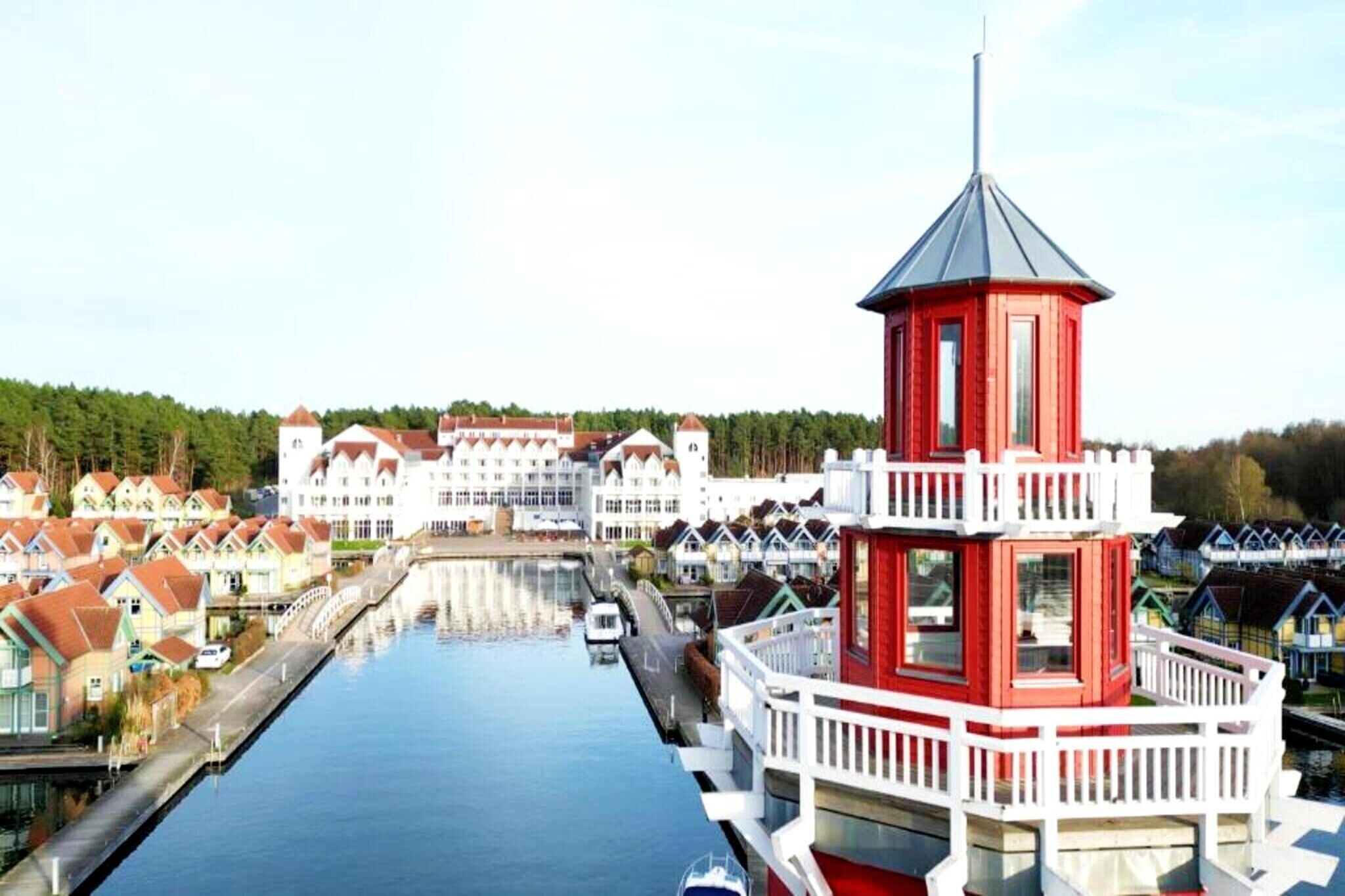 A canal with a red and white tower, surrounded by traditional houses.