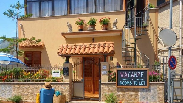 Ein Gebäude mit einem Schild, auf dem 'VACANZE ROOMS TO LET' steht, das auf freie Urlaubsräume hinweist.