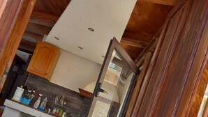 Eine Küche mit Holzbalken, einer weißen Decke und einer Tür zu einem anderen Raum.