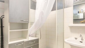 Ein Badezimmer mit Dusche, Waschbecken und einem Schrank mit Schubladen.