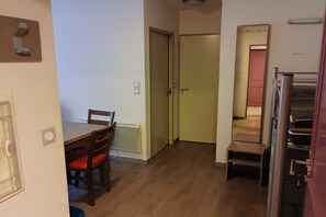 A compact kitchen with a dining table and chairs, a refrigerator, and a door leading to another room. - Ski Apartment with Pool & Free Parking (Les Angles)